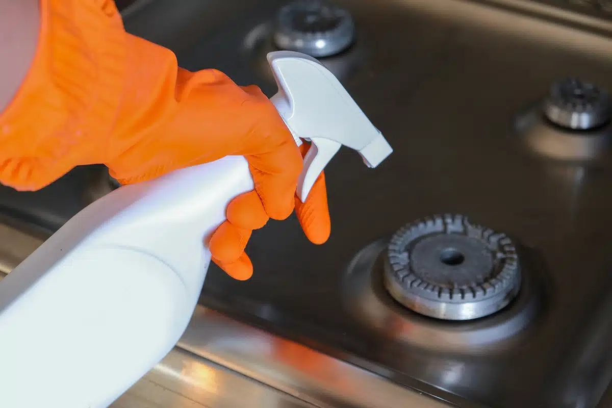 Cleaning, stove cleaner in gloved hand. Cleaning in the kitchen
